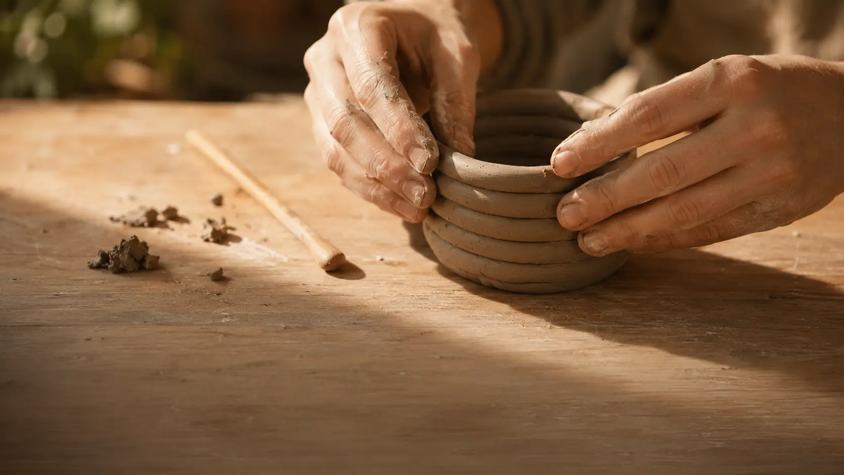 Mains montant un pot au colombin sur une table en bois, atelier céramique Lik'Art à Tunis