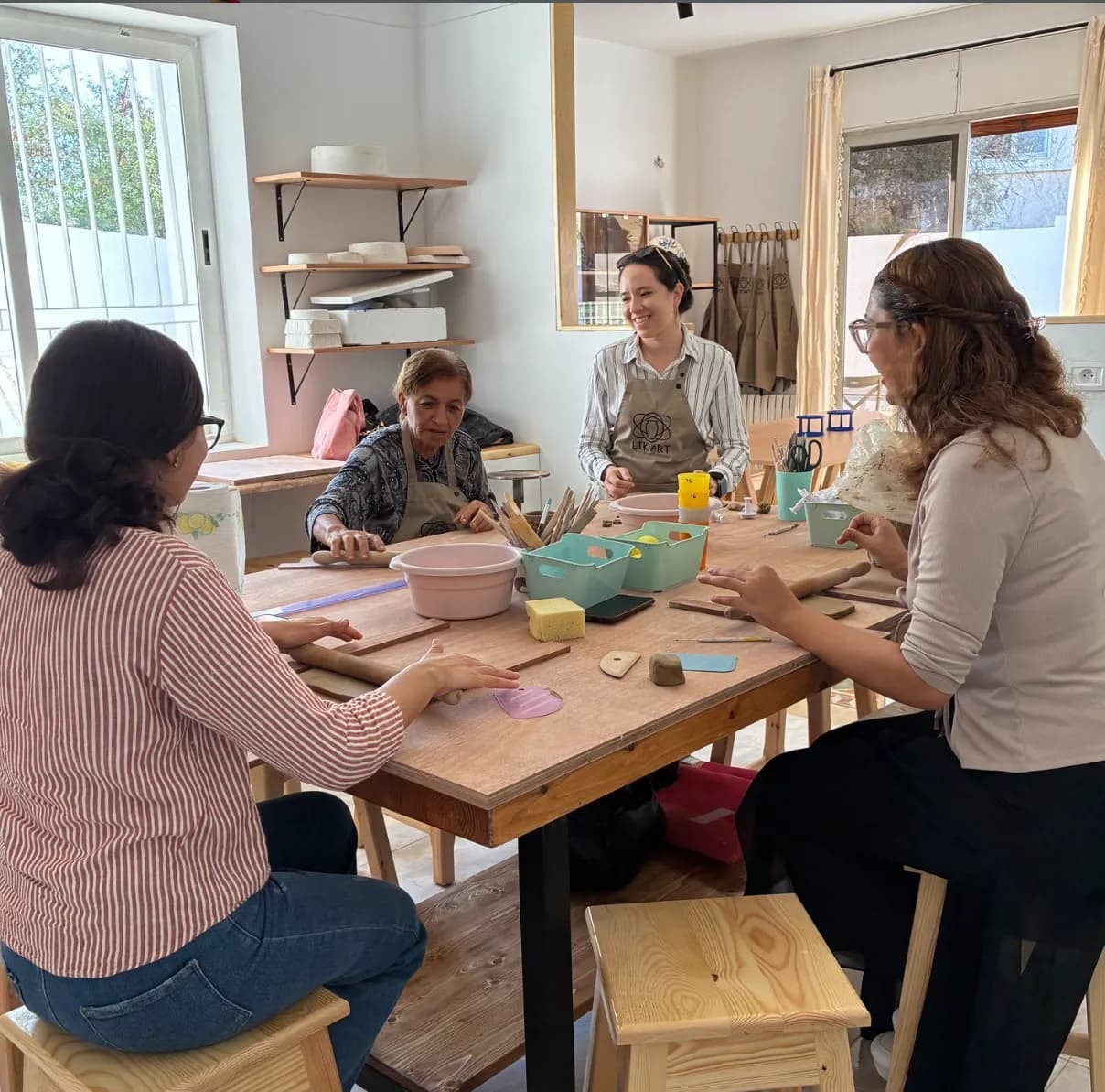 Groupe de participantes modelant l'argile autour d'une table lors d'un cours de céramique