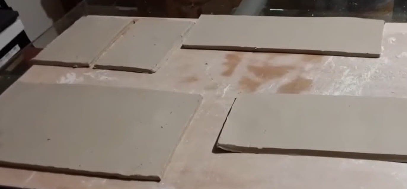 Plaques d'argile découpées et laissées à raffermir sur une table d'atelier