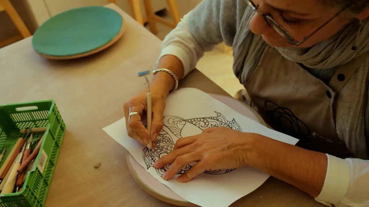 Artiste gravant un motif décoratif sur une assiette en céramique